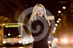 Beautiful, blonde woman in car lights in the night city.