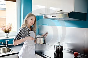 Beautiful blonde woman cooking in the modern kitchen.