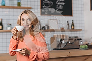 beautiful blonde woman drinking coffee and smiling at camera