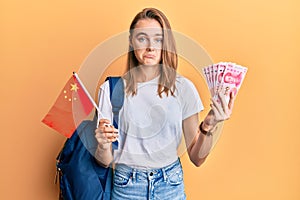 Beautiful blonde woman exchange student holding china flag and yuan banknotes depressed and worry for distress, crying angry and