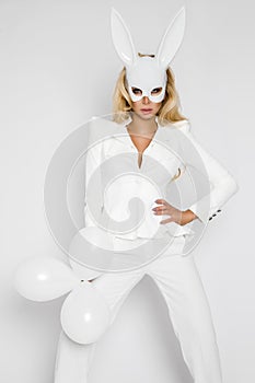 Beautiful, blonde woman girl in elegant white clothes and in a white rabbit mask and baloon