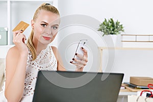 Beautiful blonde woman holding golden credit card