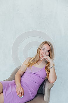 Beautiful blonde woman in light summer dress sitting on chair