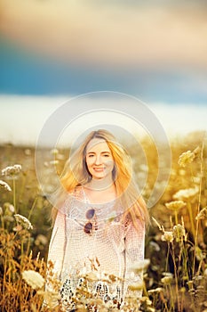 Beautiful blonde woman with long hair standing in a rural flower field outdoors