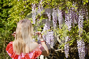 A beautiful blonde woman near a blooming wisteria