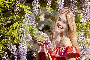 A beautiful blonde woman near a blooming wisteria