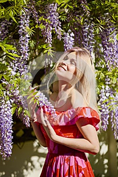 A beautiful blonde woman near a blooming wisteria