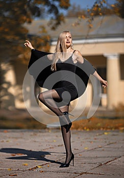 Beautiful blonde woman with perfect legs in pantyhose posing outdoor at the autumn street