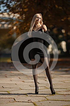 Beautiful blonde woman with perfect legs in pantyhose posing outdoor at the autumn street