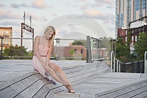 Sexy blonde model poses in park wearing pink strapless dress photo