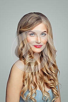 Beautiful blonde woman portrait. Elegant female model with long healthy curly hair and red lips makeup