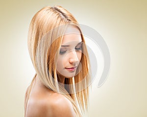 Beautiful blonde woman in profile, looking down on a light background