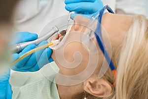 Beautiful blonde woman is receiving dental care in dentist clinic