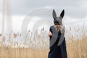 Beautiful blonde woman with scared face in black bunny mask