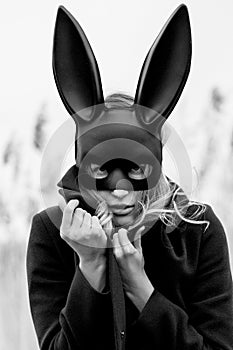 Beautiful blonde woman with scared face in black bunny mask