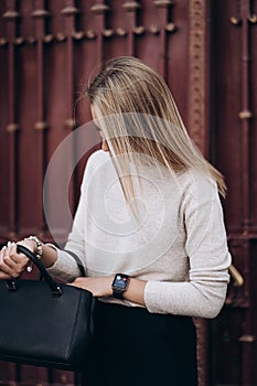 Beautiful blonde woman searching something in bag , walking on street.Portrait of stylish smiling business woman in Dark