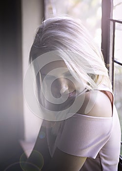 Beautiful blonde woman seated next to window in soft natural light