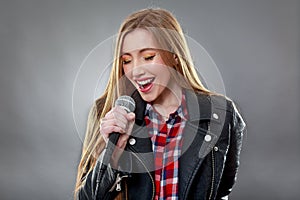 A beautiful blonde woman singing in microphone