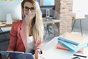 Beautiful blonde woman sit in cabinet with paperwork and laptop