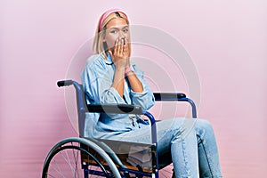 Beautiful blonde woman sitting on wheelchair laughing and embarrassed giggle covering mouth with hands, gossip and scandal concept