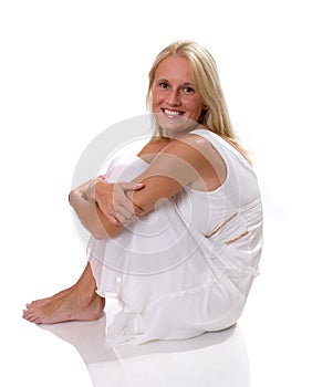 Beautiful blonde woman sitting in white dress