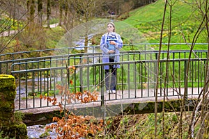 Beautiful blonde woman standing on a bridge with her little baby photo