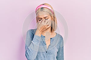 Beautiful blonde woman standing over pink background tired rubbing nose and eyes feeling fatigue and headache