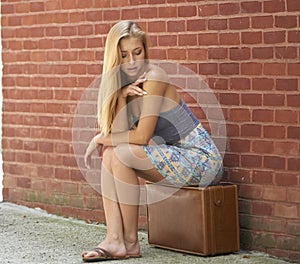 Beautiful blonde woman in strapless sundress with vintage suitcase