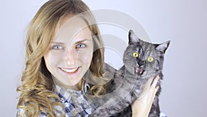 Beautiful blonde woman with a tabby british cat looking at camera
