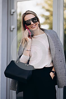 Beautiful blonde woman talking on phone walking on street.Portrait of stylish smiling business woman in Dark casual