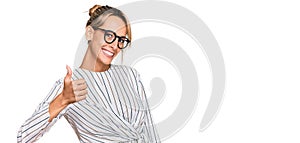 Beautiful blonde woman wearing business shirt and glasses doing happy thumbs up gesture with hand
