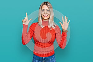 Beautiful blonde woman wearing casual clothes showing and pointing up with fingers number seven while smiling confident and happy