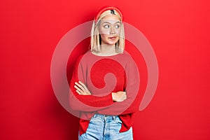 Beautiful blonde woman wearing casual red sweater smiling looking to the side and staring away thinking