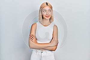 Beautiful blonde woman wearing casual style with sleeveless shirt smiling looking to the side and staring away thinking