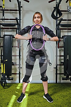 Beautiful blonde woman wearing in sensors and belts, fastens with velcro is practicing EMS fitness in a gym, building up