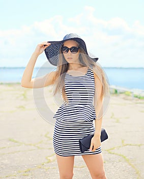 Beautiful blonde woman wearing a striped dress, straw hat