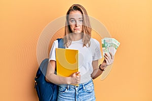 Beautiful blonde woman wearing student backpack and holding 50 hong kong banknotes depressed and worry for distress, crying angry