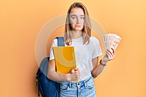 Beautiful blonde woman wearing student backpack and holding 50 turkish lira depressed and worry for distress, crying angry and