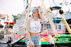 Beautiful blonde woman wearing sunglasses close-up portrait of a young girl hipster in the park attraction Street fashion con