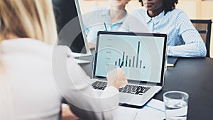 Beautiful blonde woman working modern laptop in office. Female hand pointing to the computer screen. Group of girls coworkers disc