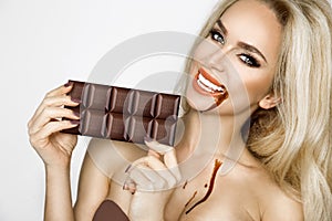 Beautiful, blonde women with green eyes sensually eating tasty chocolate.