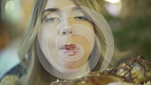 Beautiful blonde young greedy woman biting huge pieces of meat eating with hands angry inappropriate in close up view