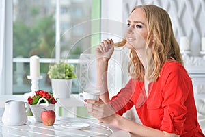 Beautiful blonde young woman drinking tea at kitchen