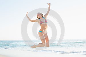 Beautiful blonde young woman jumping on beach