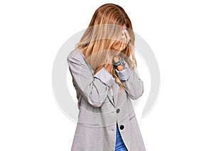 Beautiful blonde young woman wearing business clothes with sad expression covering face with hands while crying