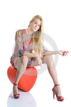 Beautiful blondy sitting on red heart and posing photo