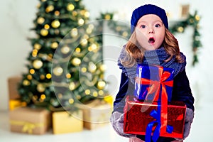 Beautiful blone little girl in the winter warm hat and scarf feeling happy and wish a good things on a Christmas