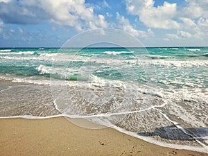 Beautiful blue aquamarine colour sea ocean water landscape with white foam. Seascape nature with waves, blue sky and sandy beach