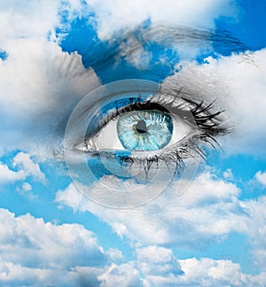 Beautiful blue eye against blue clouds - Spiritual concept