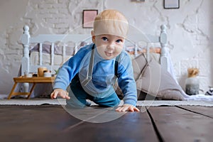 Beautiful blue-eyed baby crawling on the wooden floor